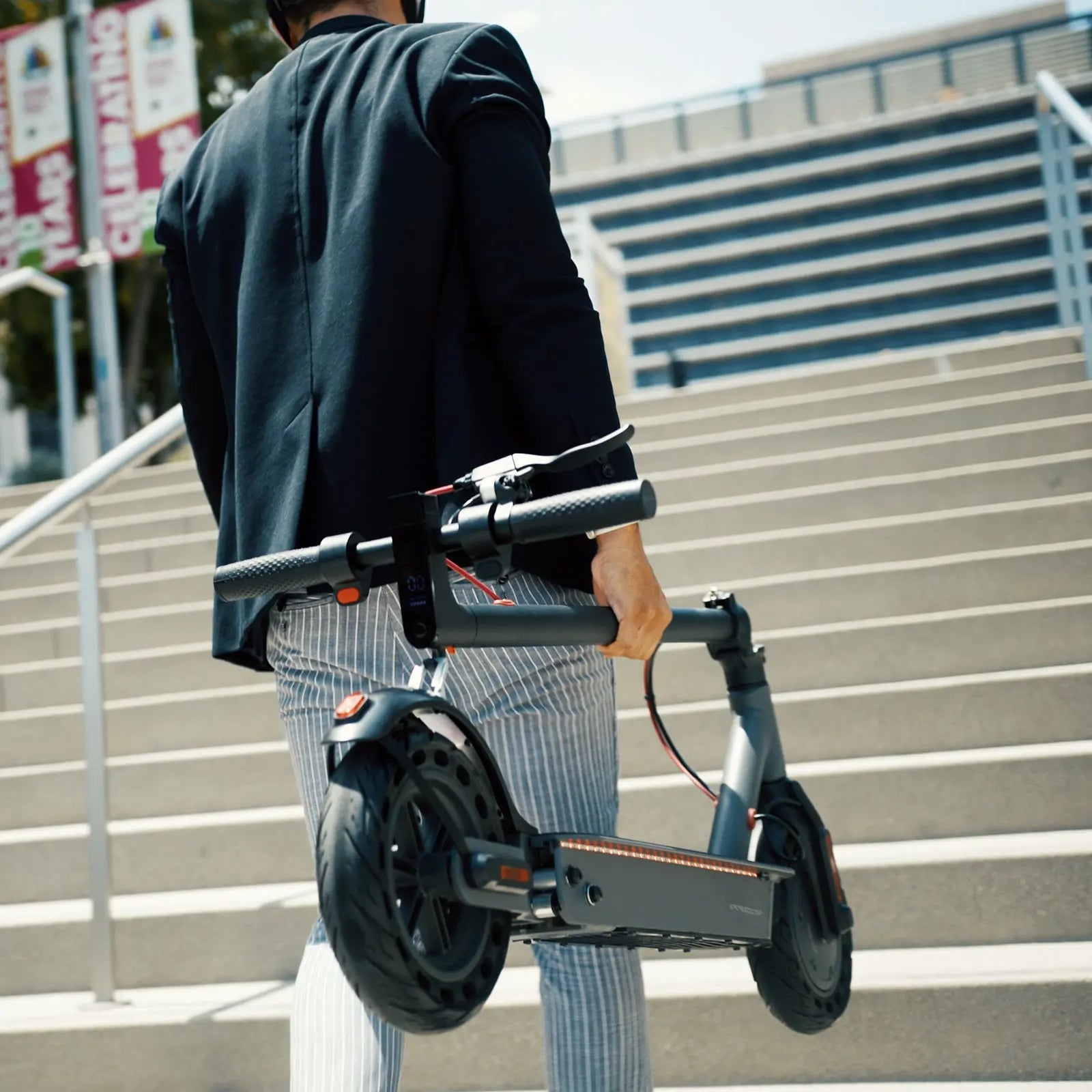 Person carrying a folded Hiboy S2 Pro electric scooter near an outdoor staircase